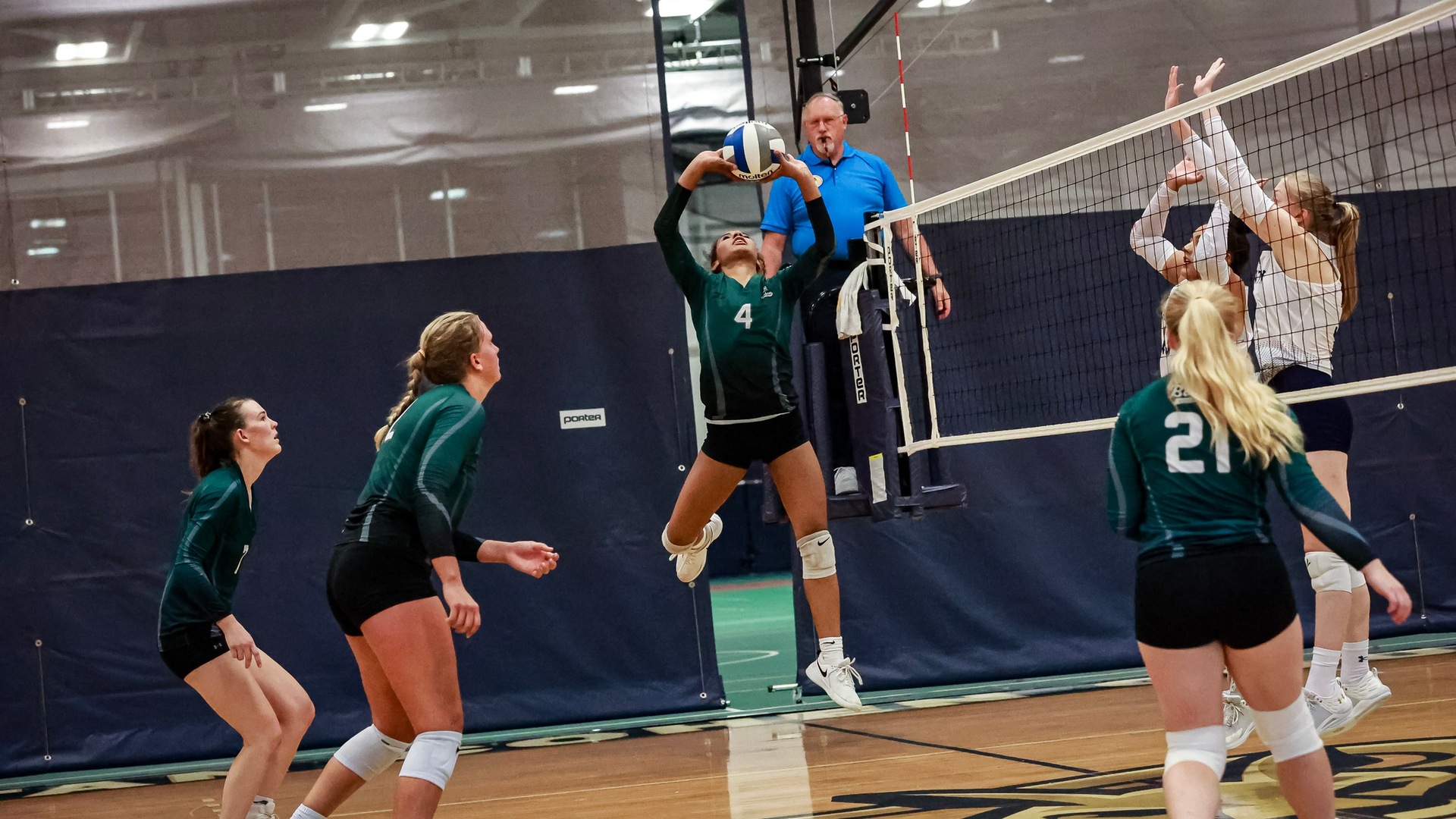 Kaliyah Davis (#4, center) appears to float in mid-air as teammates Alli Cherry (#5, left), Finnley Jacobson (#12, second from left), and McKenna Verhagen (#21, right) look on (Mercedes Rideout photo). Thumbnail
