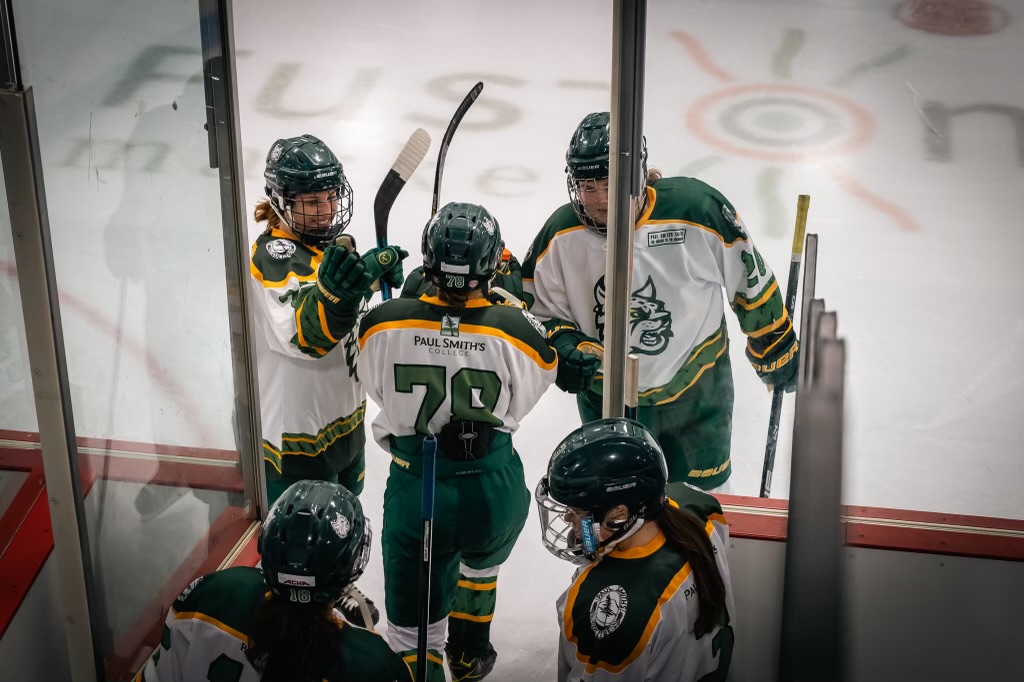 Members of the Paul Smith's College women's hockey team get each other ready before going out on the ice (Zach Thoren photo). Thumbnail